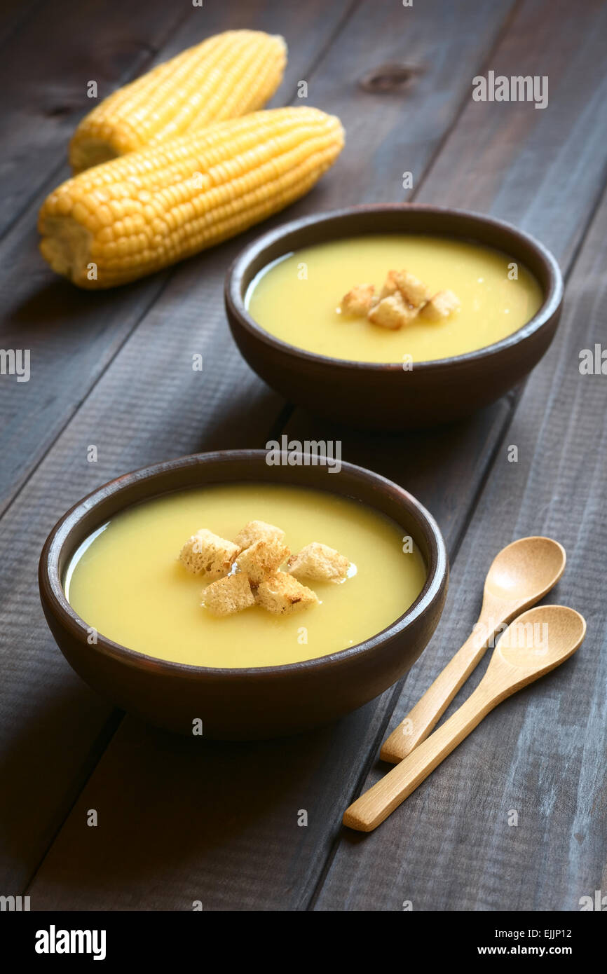 Zwei Schüsseln mit Creme von Mais-Suppe mit Croutons obenauf, fotografiert auf dunklem Holz mit natürlichem Licht (Tiefenschärfe) Stockfoto