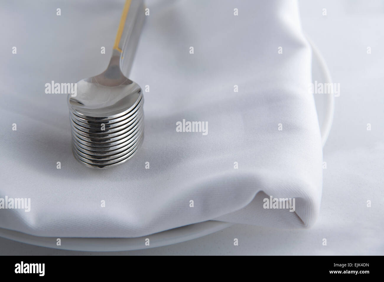 Dessertlöffel über eine weiße Serviette in einem Teller Stockfoto