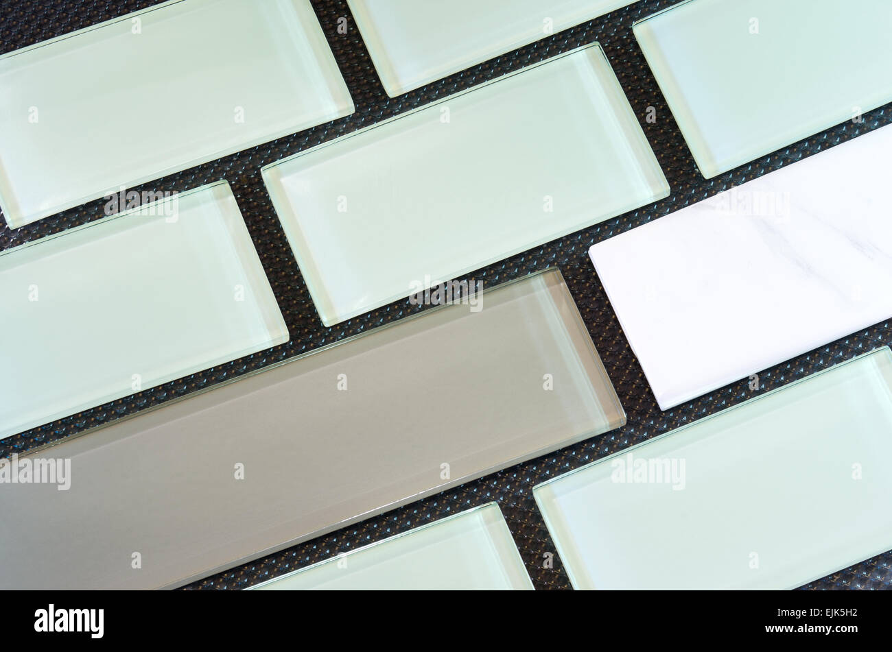 grün weiß und Taupe farbige Glas und Porzellan-u-Bahn-Fliese oder Backsplash vor schwarzem Hintergrund in Reihen angeordnet Stockfoto