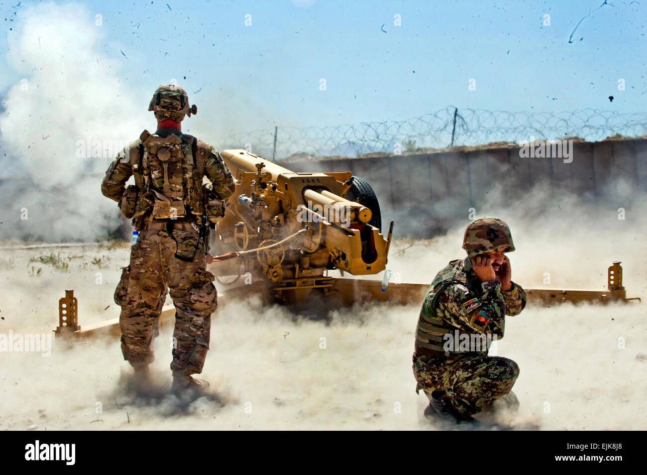 Ein US-Soldat aus Batterie B, 5. Bataillon, 25. Feldartillerie-Regiment, 4th Brigade Combat Team, 10th Mountain Division links beobachtet das Abfeuern von einer d-30 122 mm Haubitze von Afghan National Army Soldaten aus 4. Kandak, 3. Brigade, 201. Corps, während Zertifizierung Übungen auf Forward Operating Base Tagab, Kapisa Provinz, Afghanistan, 5. September 2013. Batterie B, stationiert in FOB Gamberi in Provinz Laghman, geht in Ostafghanistan, Beratung und Unterweisung Artillerie Soldaten auf die richtige Handhabung des D-30s, ein sowjetischer schwerer Artillerie Waffe in der Lage, ansprechende Ziel Stockfoto