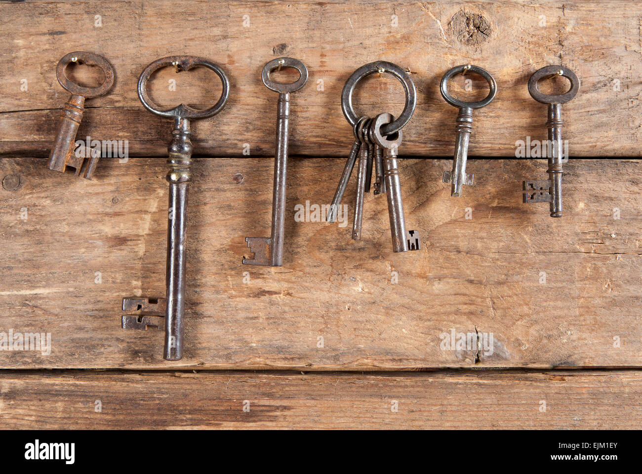 Rostige alte Schlüssel hängen vor dem hölzernen Hintergrund Stockfoto