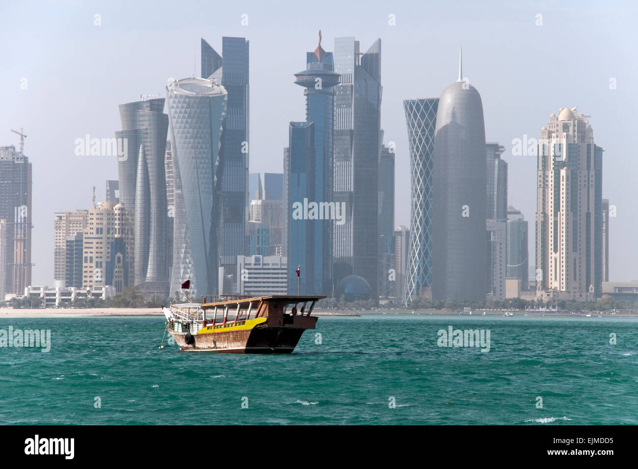 Eine Dhau-Boot pflügt die Gewässern des Arabischen Golfs in der Nähe von der Skyline von Doha, der Hauptstadt von Gulf Nation von Katar. Stockfoto