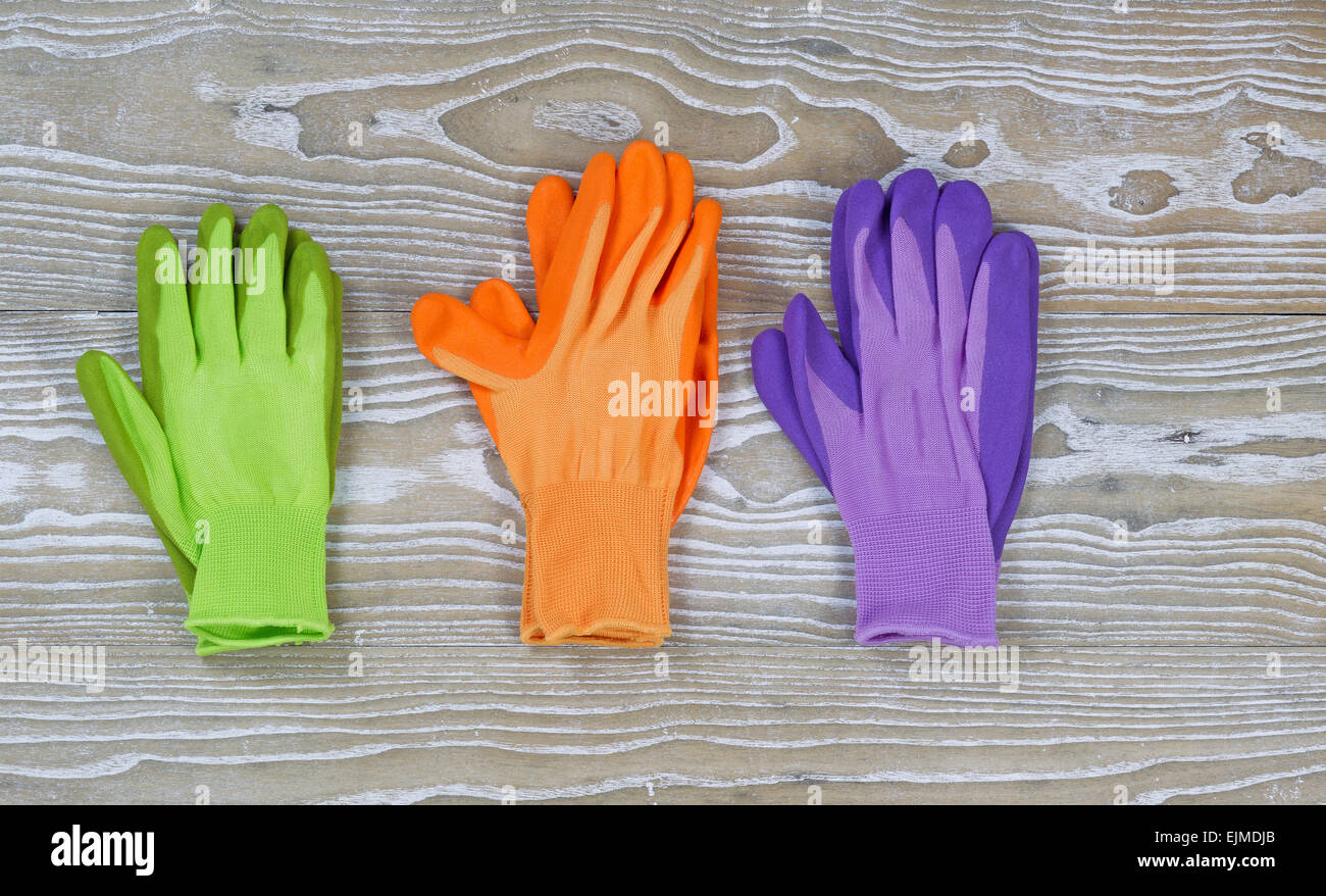 Neue farbenfrohe Garten Handschuhe auf rustikalen hölzernen Tafeln. Layout im Querformat. Stockfoto
