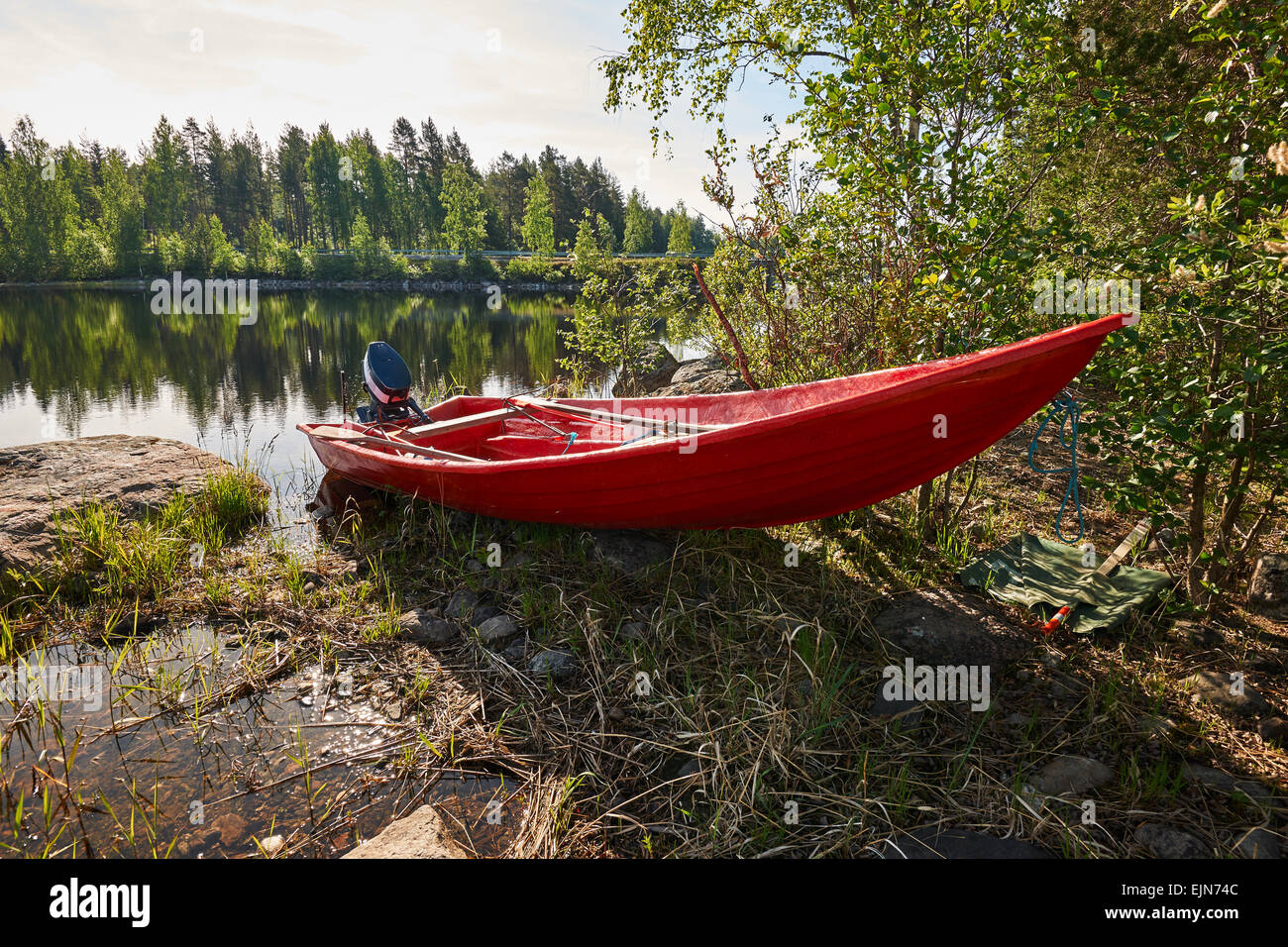 Rotes Bootsmotor an einem See in einem finnischen Frühlingstag bei Gegenlicht fotografiert Stockfoto