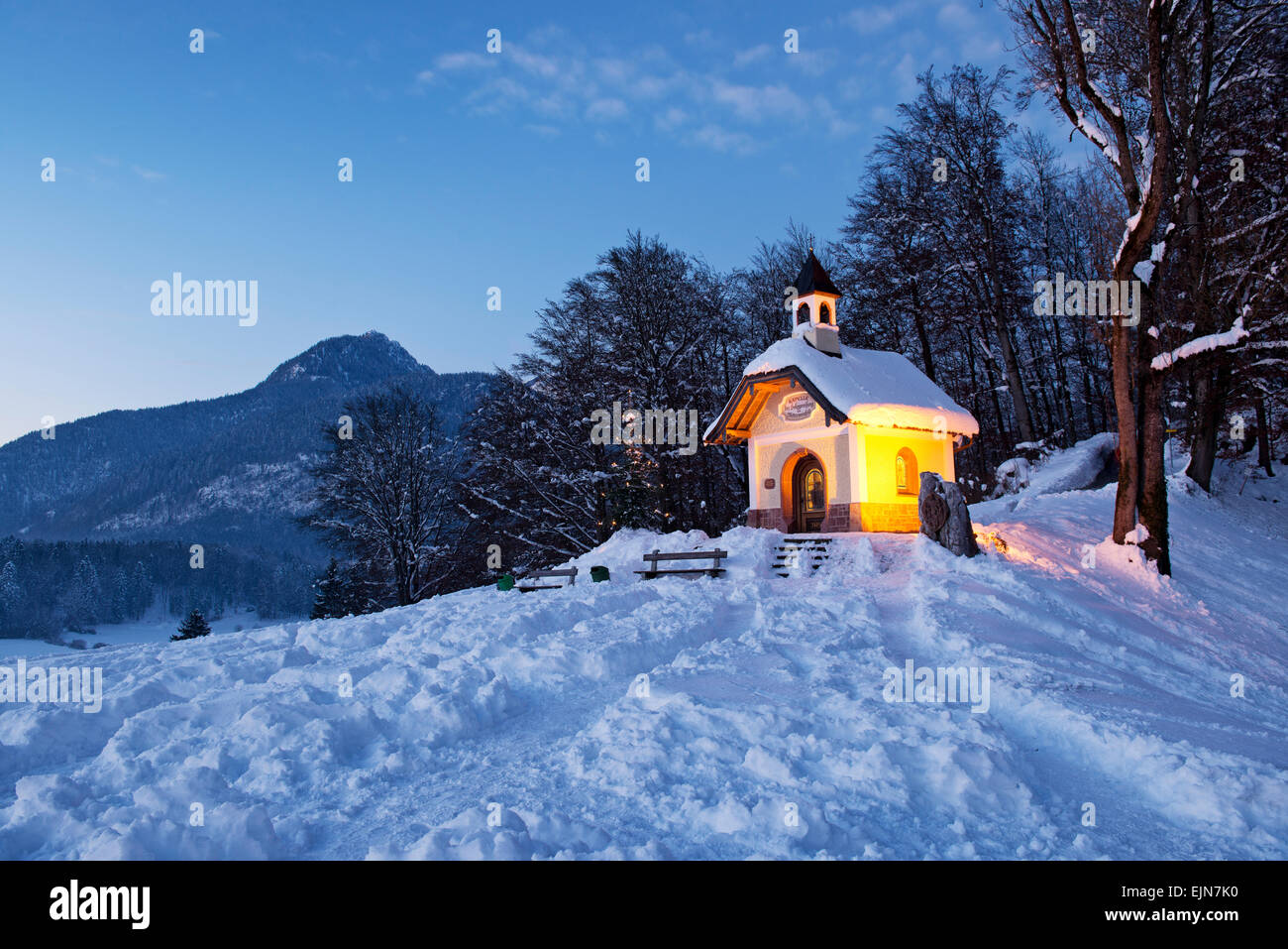 Kapelle am Berchtesgadens in Berchtesgaden bei Sonnenuntergang mit Weihnachtsbaum vor Berg, Deutschland. Stockfoto