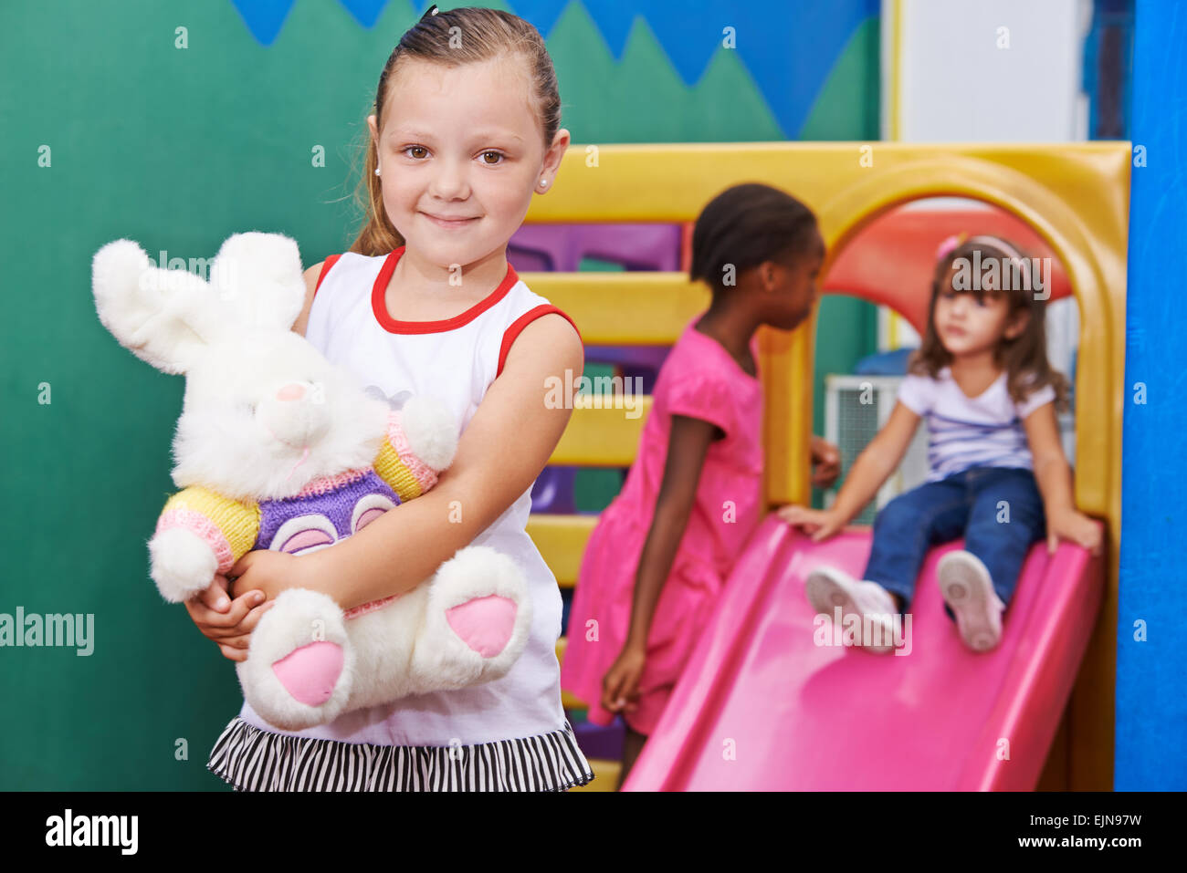 Glückliches Mädchen hält ein Stofftier im kindergarten Stockfoto