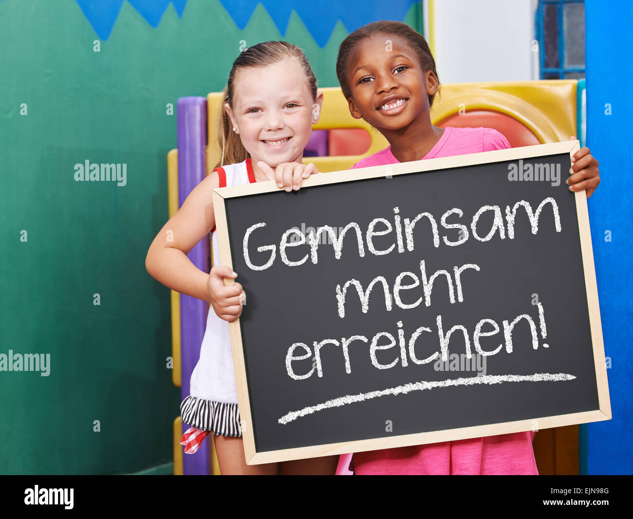 Kinder halten Tafel Sprichwort auf Deutsch "Gemeinsam Mehr u-" (gemeinsam mehr erreichen) Stockfoto
