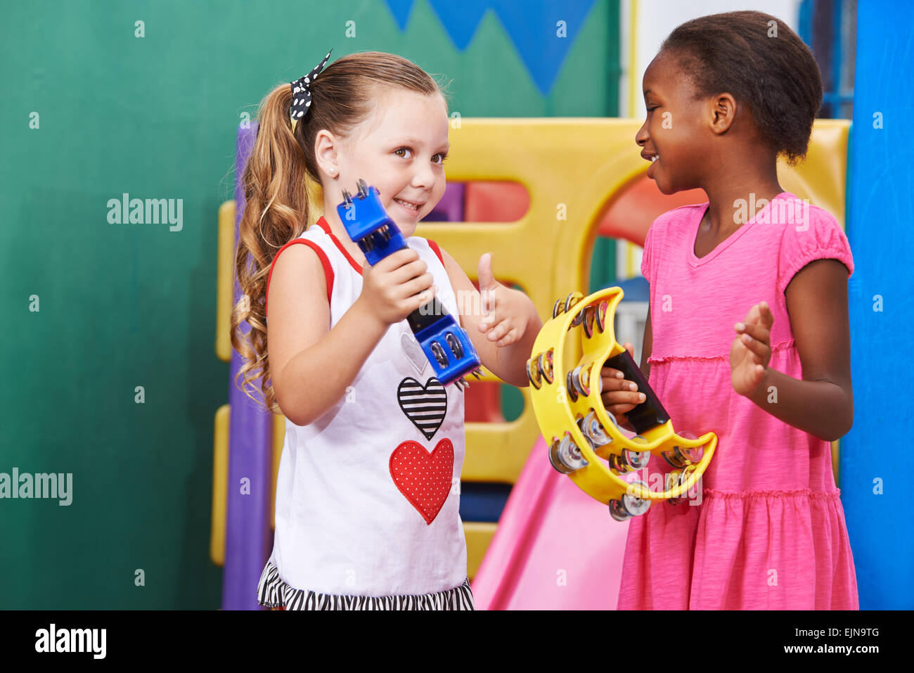 Zwei Mädchen spielen Musik mit Tamburin in einem kindergarten Stockfoto