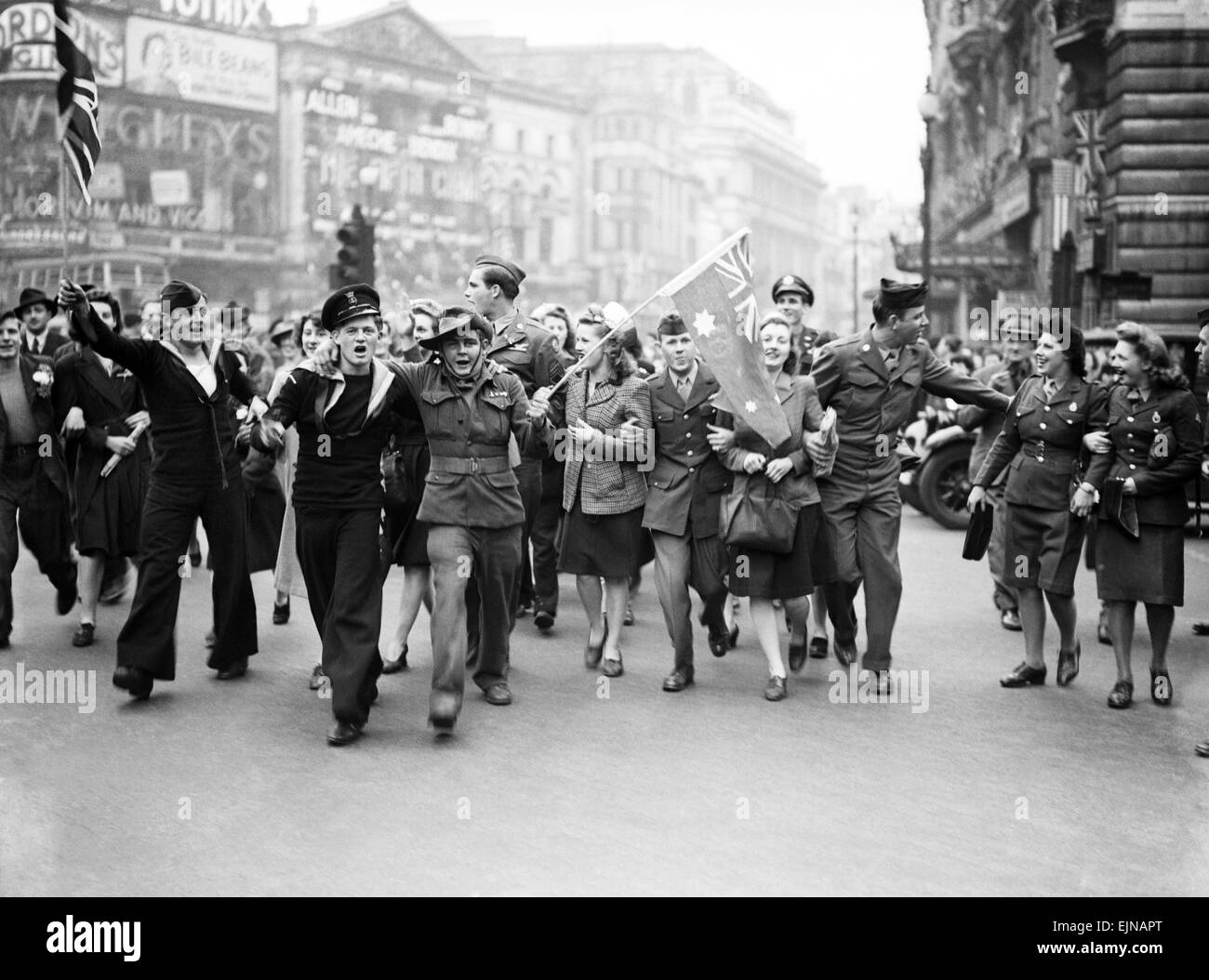 VE Day Feierlichkeiten in London am Ende des zweiten Weltkriegs. Riesige Menschenmengen versammelten sich um Piccadilly Circus während der Feierlichkeiten mit Soldatinnen und Soldaten wehende Fahnen ihrer Nation. 8. Mai 1945. Stockfoto