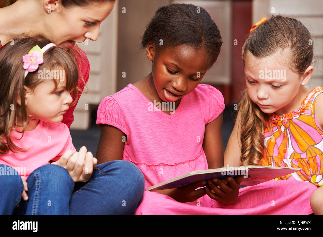 Kinder lernen mit Kindergärtnerin in der Vorschule zu lesen Stockfoto
