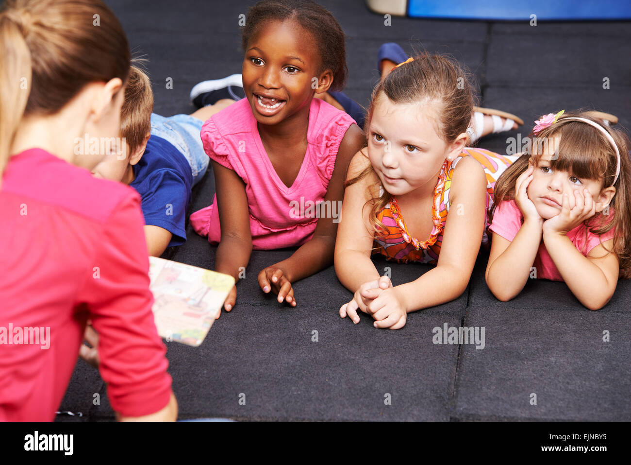 Glückliche Kinder hören Märchen Buch in der Vorschule von Kindergärtnerin gelesen Stockfoto