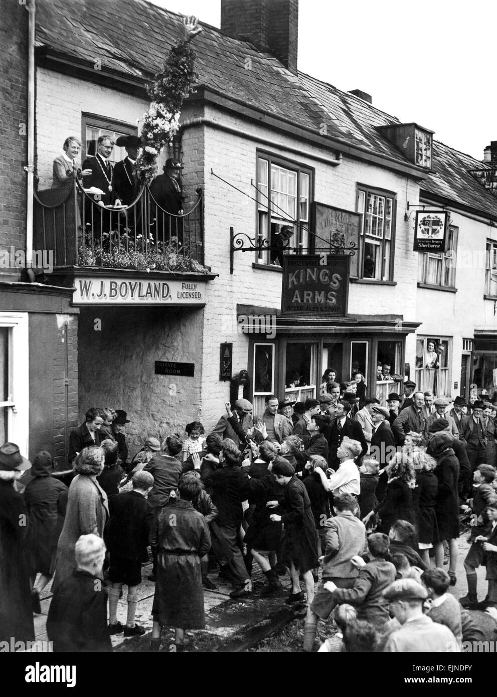 Werfen heißen Pfennige für Kinder im Honiton Fair Devon. Die heiße Pfennige Preisverleihung findet jährlich am ersten Dienstag nach dem 19 Juli in der Hauptstraße der Stadt und Termine bis ins 13. Jahrhundert zurück. Die Zeremonie hat seine Wurzeln in der Praxis der Landadel, die Freude an heißen Pfennige aus Windows, Bauern, werfen eine scheinbar philanthropischen Geste, was zu Verbrennungen. Der Brauch hatte auch den Zweck des Menschen ermutigen, in die Stadt aus der Umgebung für eine spätere Messebesuch zu reisen. 20. Juli 1943 P029149 Stockfoto