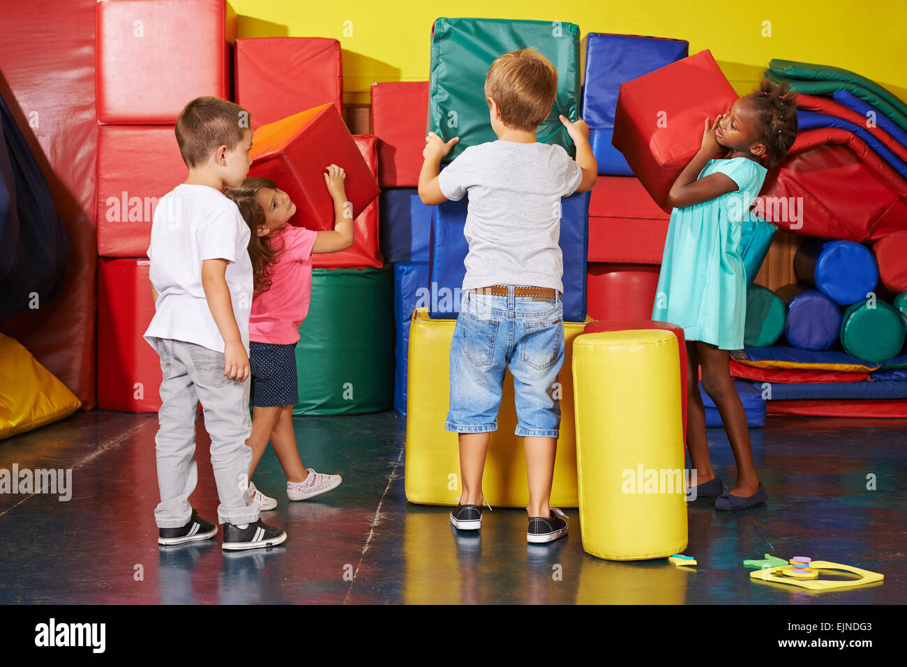 Viele Kinder zusammen in eine Vorschule Fitnessraum aufräumen helfen Stockfoto