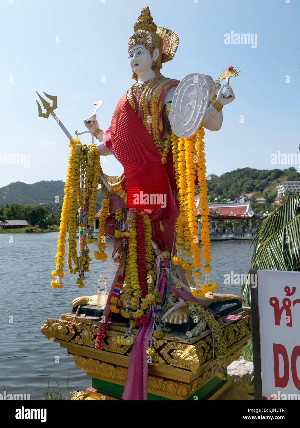 Eine Statue in floral Angebote an der Einfahrt zu einem Tempel von Wat Plai Laem auf Koh Samui abgedeckt Stockfoto