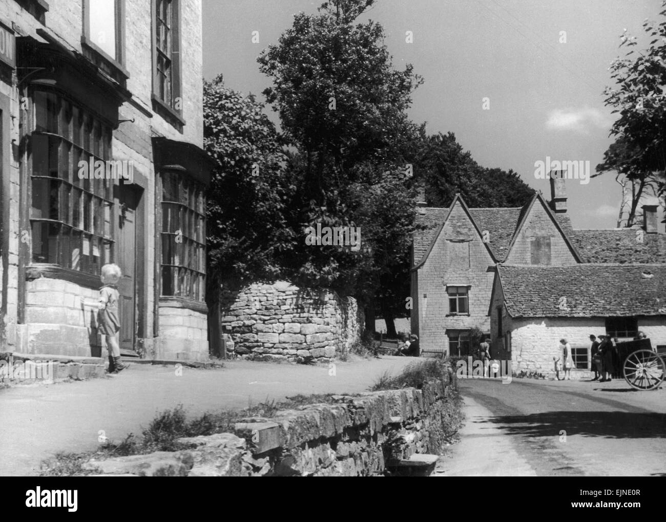 Kleiner Junge peering Theough ein Schaufenster in die Cotswold Dorf Uley nahe Dursley in Gloucestershire. Ca. 1935. Stockfoto