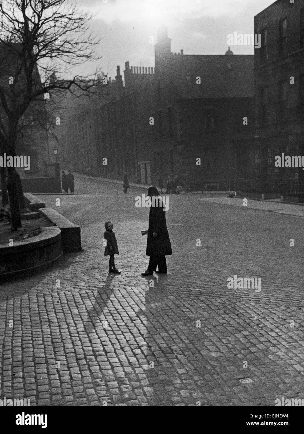 Edinburgh Straßenszenen Polizist im Gespräch mit Kind auf einer gepflasterten Straße in Edinburgh, Schottland verloren. Malerische Atospheric verlassene Straßen einsam unheimliche ca. 1930er Jahre Stockfoto