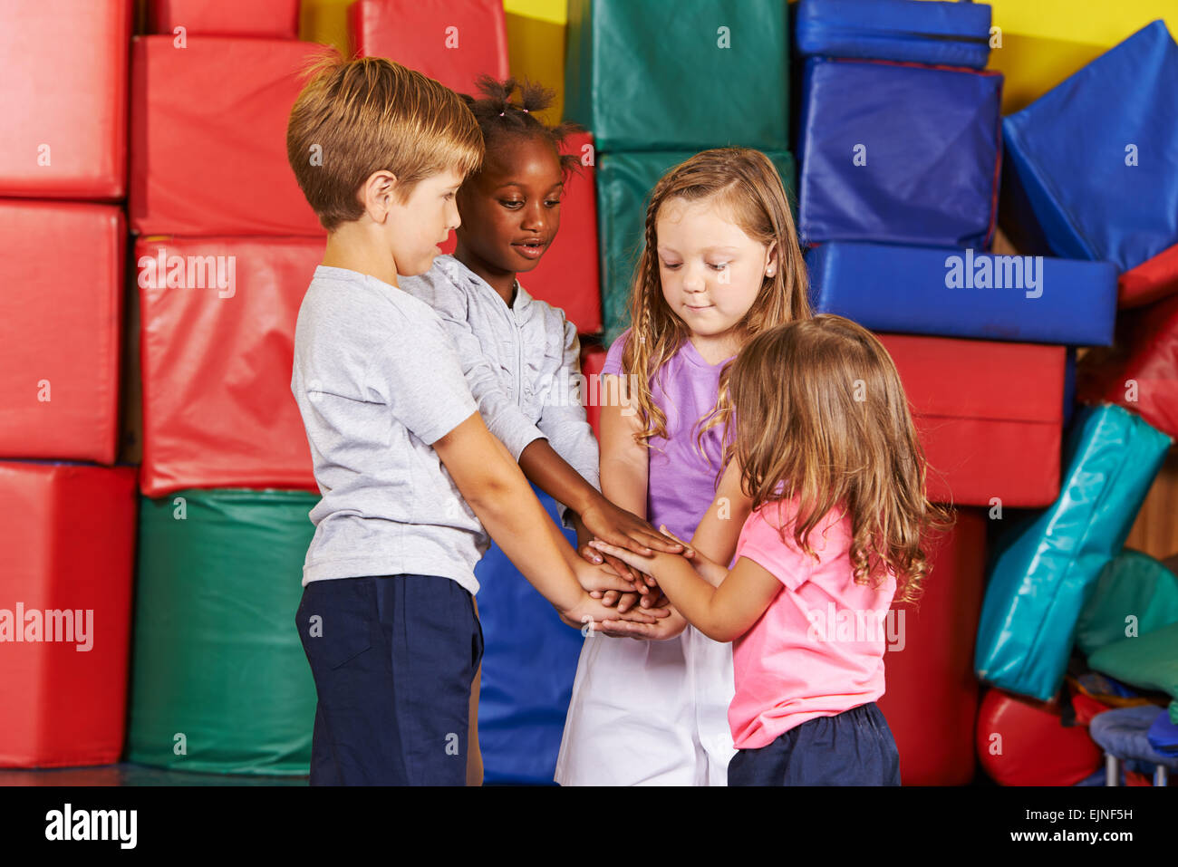 Viele Kinder, die ihre Hände in Kindergarten-Turnhalle stapeln Stockfoto