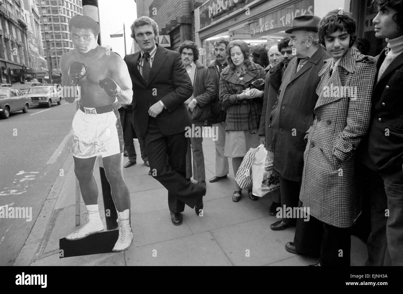 Boxer Joe Bugner warten an einer Bushaltestelle mit einer Lebensgröße herausgeschnitten Mohammad Ali auf seinem Weg zu einer Pressekonferenz im Londoner Sportsmans Club, wo er Jimmy Ellis kennenlernte, die er im Wembley-Stadion am Dienstag, 12. November 1974 trifft. November 1974 Stockfoto