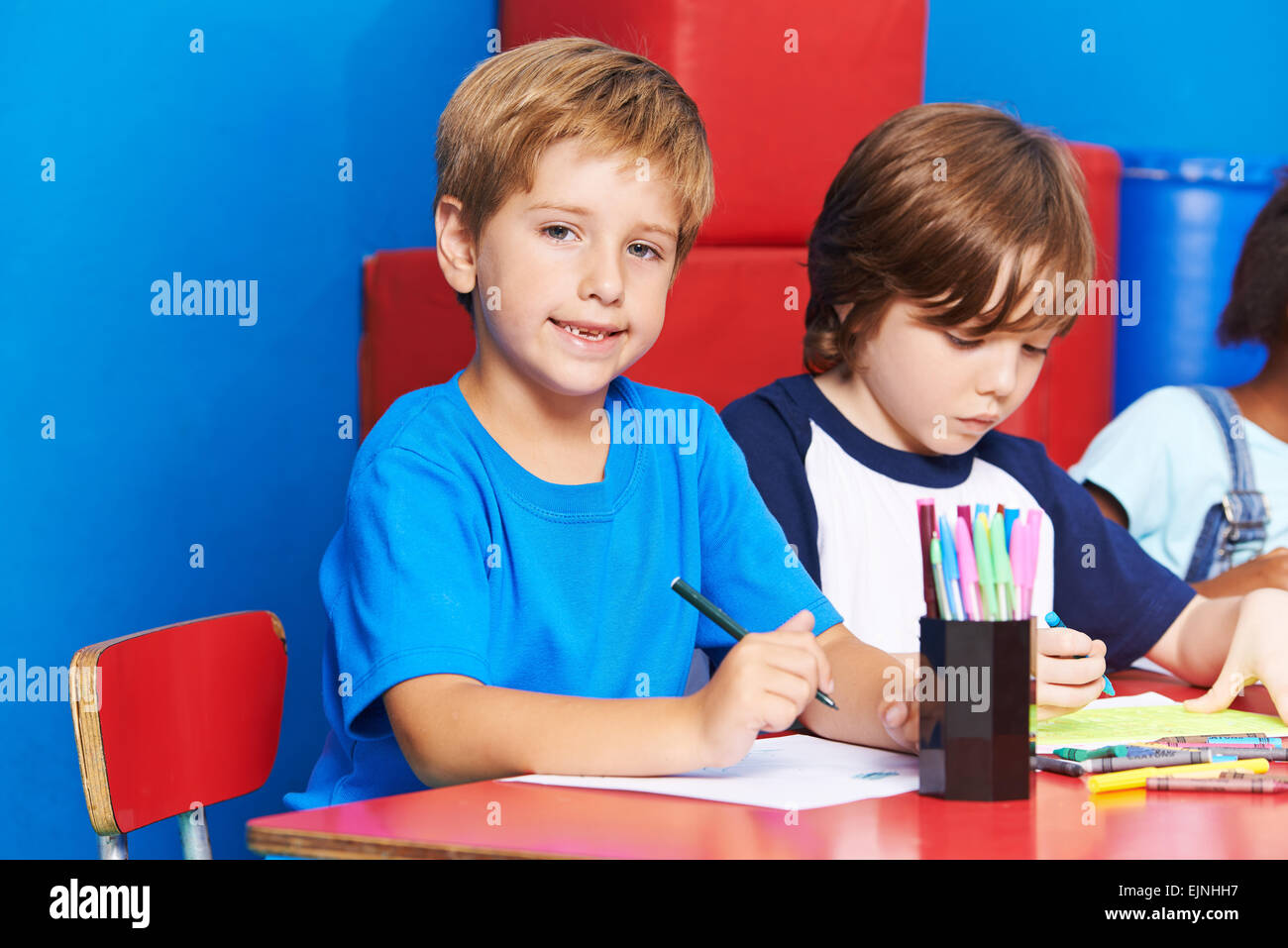 Glückliches Kind malen mit Filzstift im Kindergarten auf einem Tisch Stockfoto