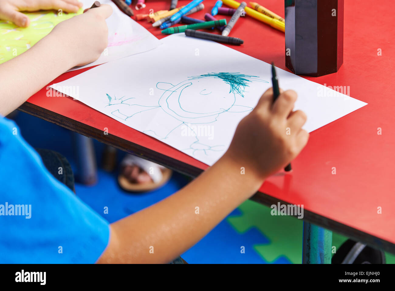 Kind mit Filzstift im Kindergarten Person auf Papier zeichnen Stockfoto
