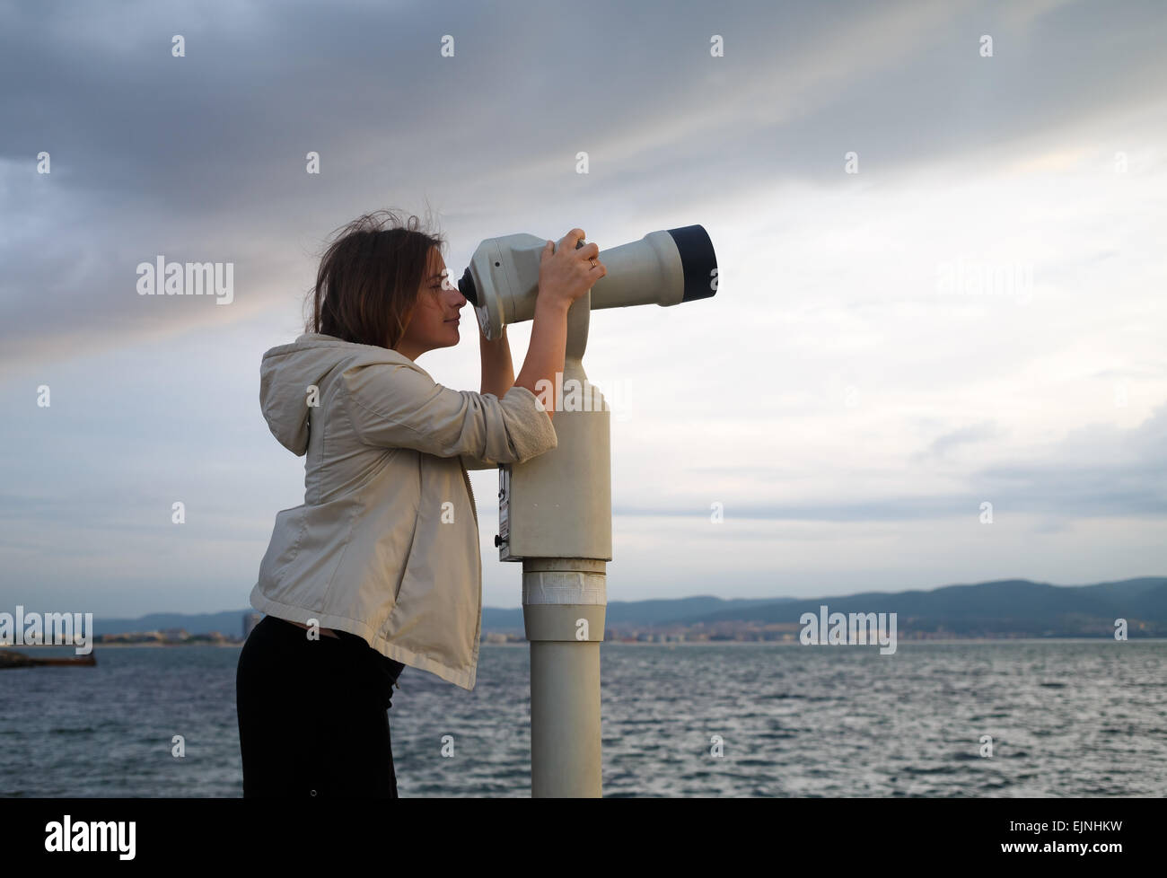 Hübsche junge Frau mit einer Münze betrieben binokularen genießen einen tollen Blick auf das Schwarze Meer. Am frühen Morgen. Geringe Schärfentiefe Stockfoto