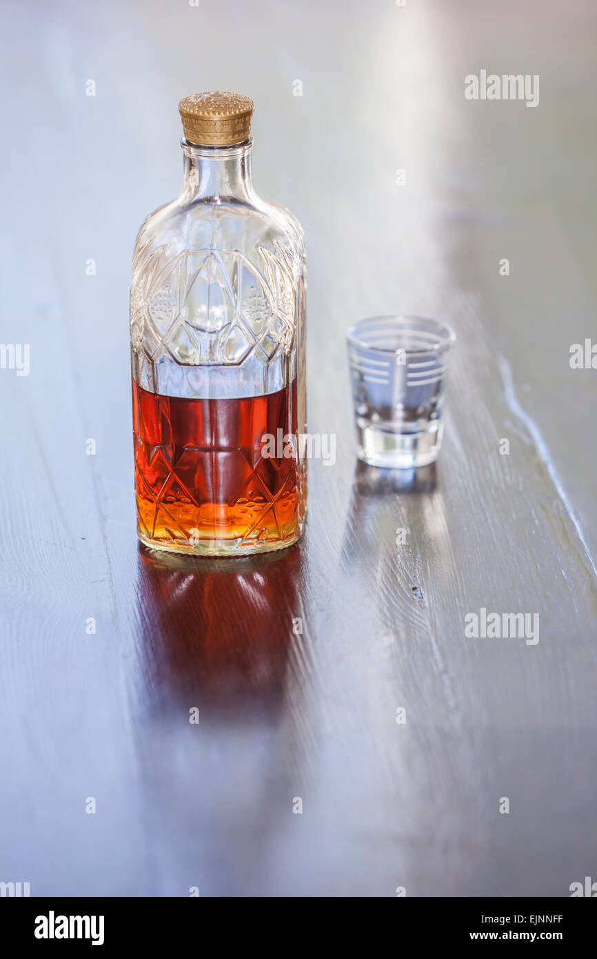 Shot-Glas und halb voll Whisky-Flasche leer. Stockfoto