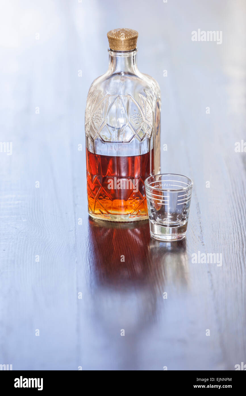Leere Schnapsglas mit halb voll Whisky-Flasche Stockfoto