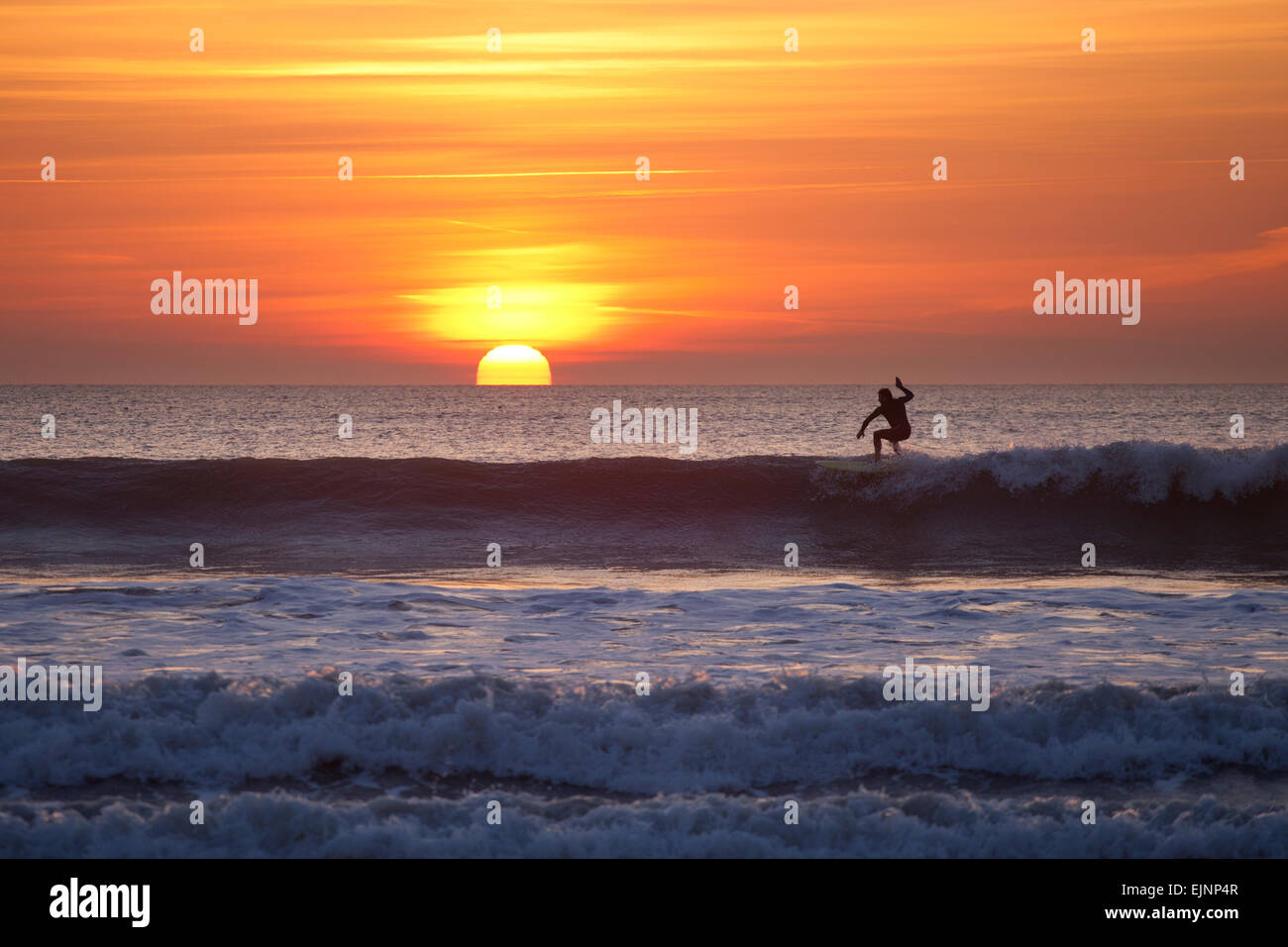 Surfer reiten die Wellen bei Sonnenuntergang mit Meer und Sonne, Saunton Sands, North Devon einstellen Stockfoto