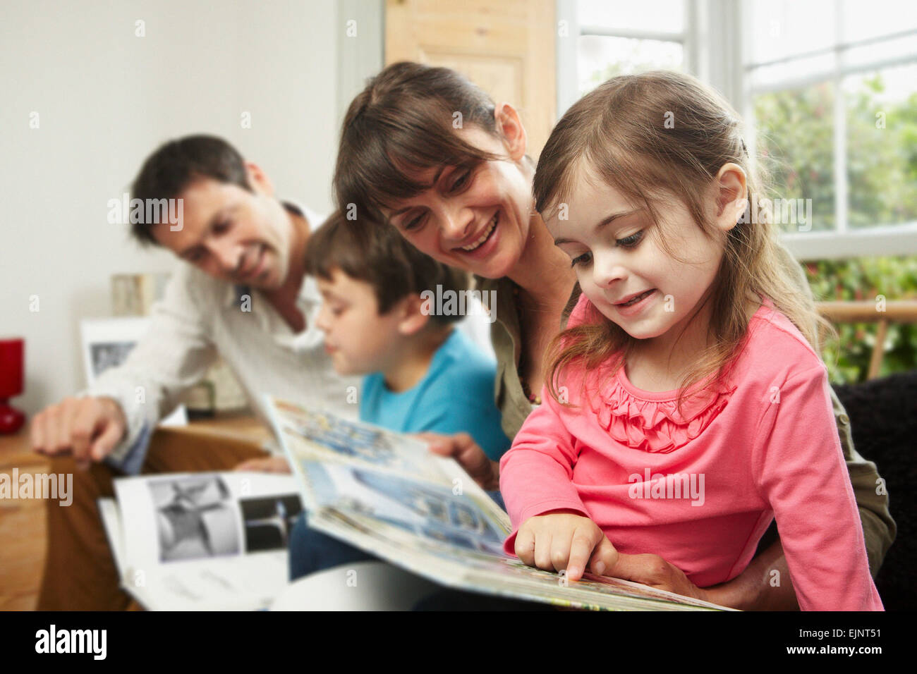 Eine Familie, zwei Eltern und zwei Kinder zu Hause gemeinsam lesen. Stockfoto