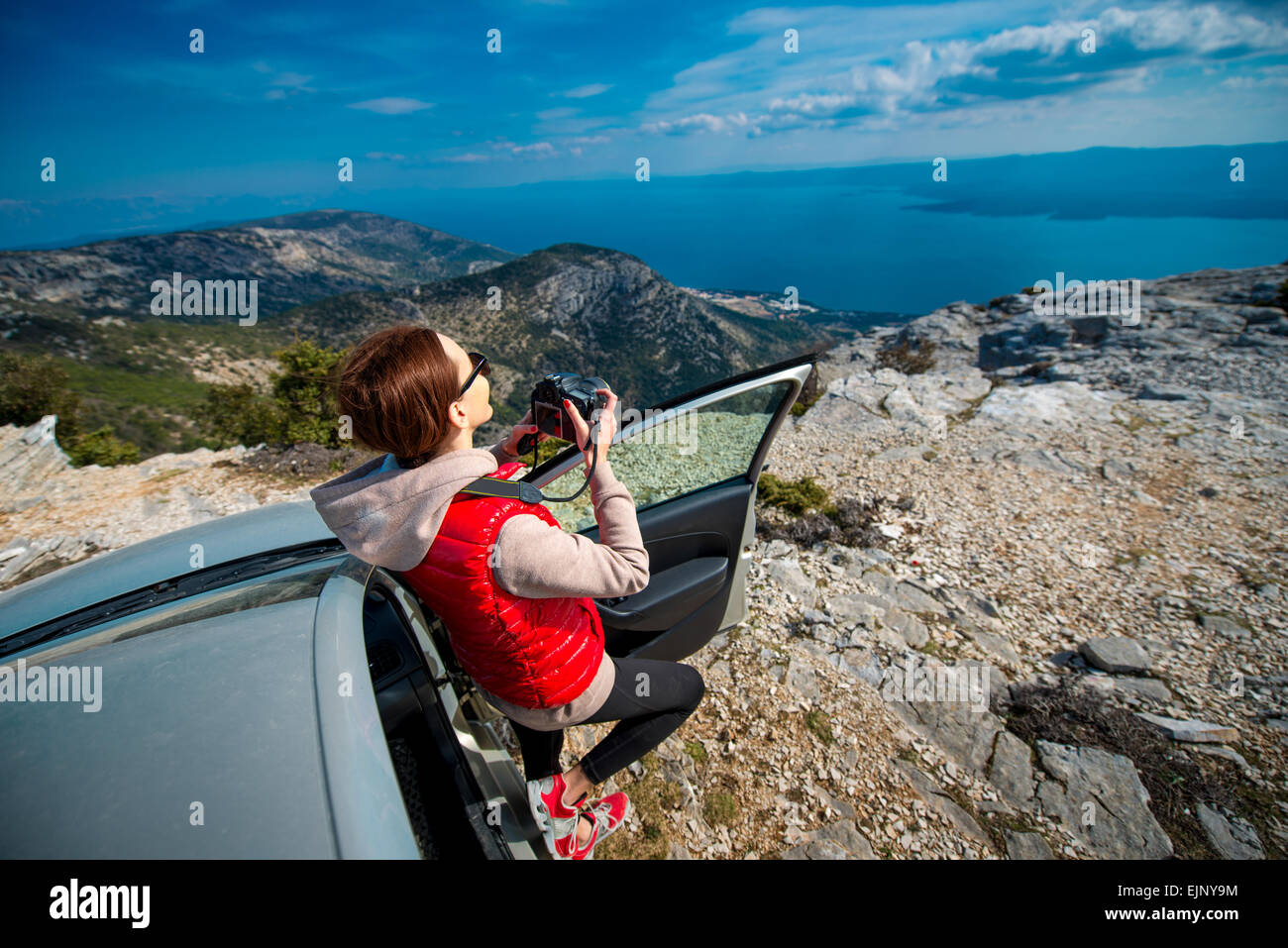 Frau-Fotograf mit Auto auf Berg Stockfoto
