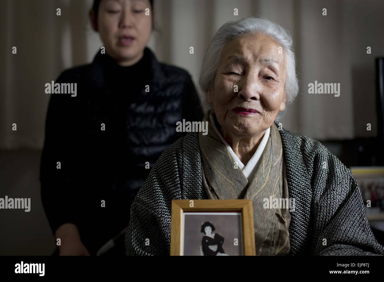 10. März 2015 - Kamaishi, Japan - CHIKANO FIJIMA (aka TSUYAKO ITO) (rechts), 89, die ältesten Geisha von Kamaishi, Japan, und ein Lehrer der traditionellen japanischen Tanz hält ein Foto von sich selbst als eine 28 Jahre alte Geisha. Frau Fujima entkam der Tsunami-Katastrophe, aber ihre Heimat verloren und lebt jetzt in Notunterkünften für die vergangenen vier Jahre. Langzeitfreund Toshiko Miyazaki sitzt hinter ihr. (Kredit-Bild: © Earnie Grafton/ZUMA Draht) Stockfoto