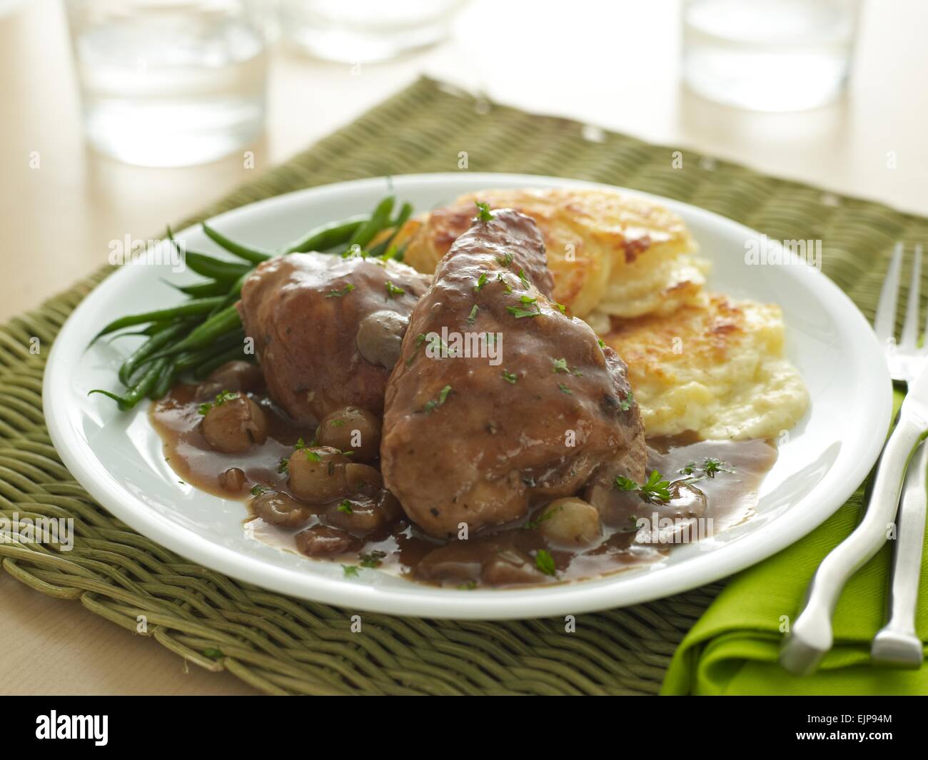 Mahlzeit Huhn in Rotwein und Pilzsauce weiße Platte serviert mit Dauphinoise Kartoffeln und Bohnen Französisch Stockfoto