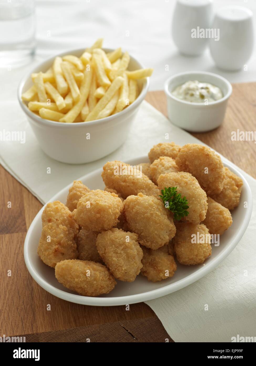 Panierter Fisch Nuggets Chips separaten Schüsseln Tartare Sauce Menage set Glas water.wooden board Stockfoto