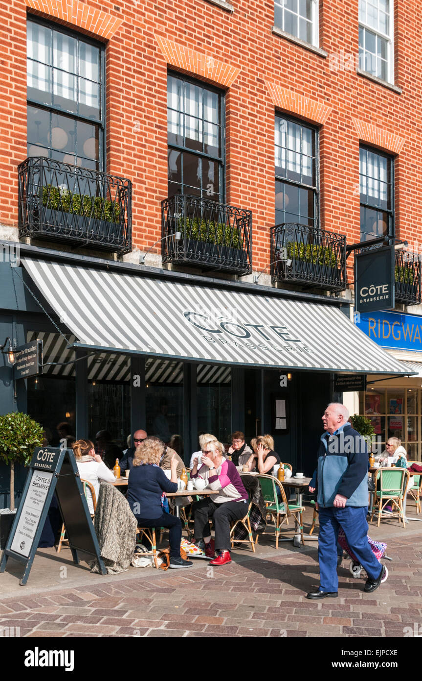 Mann zu Fuß vorbei an Kunden saßen draußen die Cote Brasserie in Exeter Stockfoto