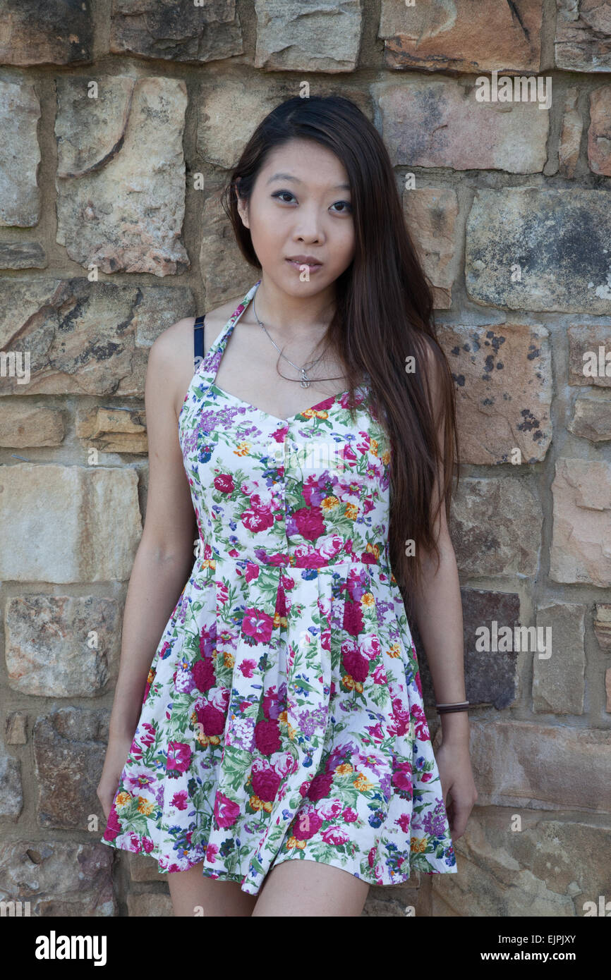 Ziemlich Asian Frau, die im Freien in einem geblümten Kleid, nachdenklich Stockfoto