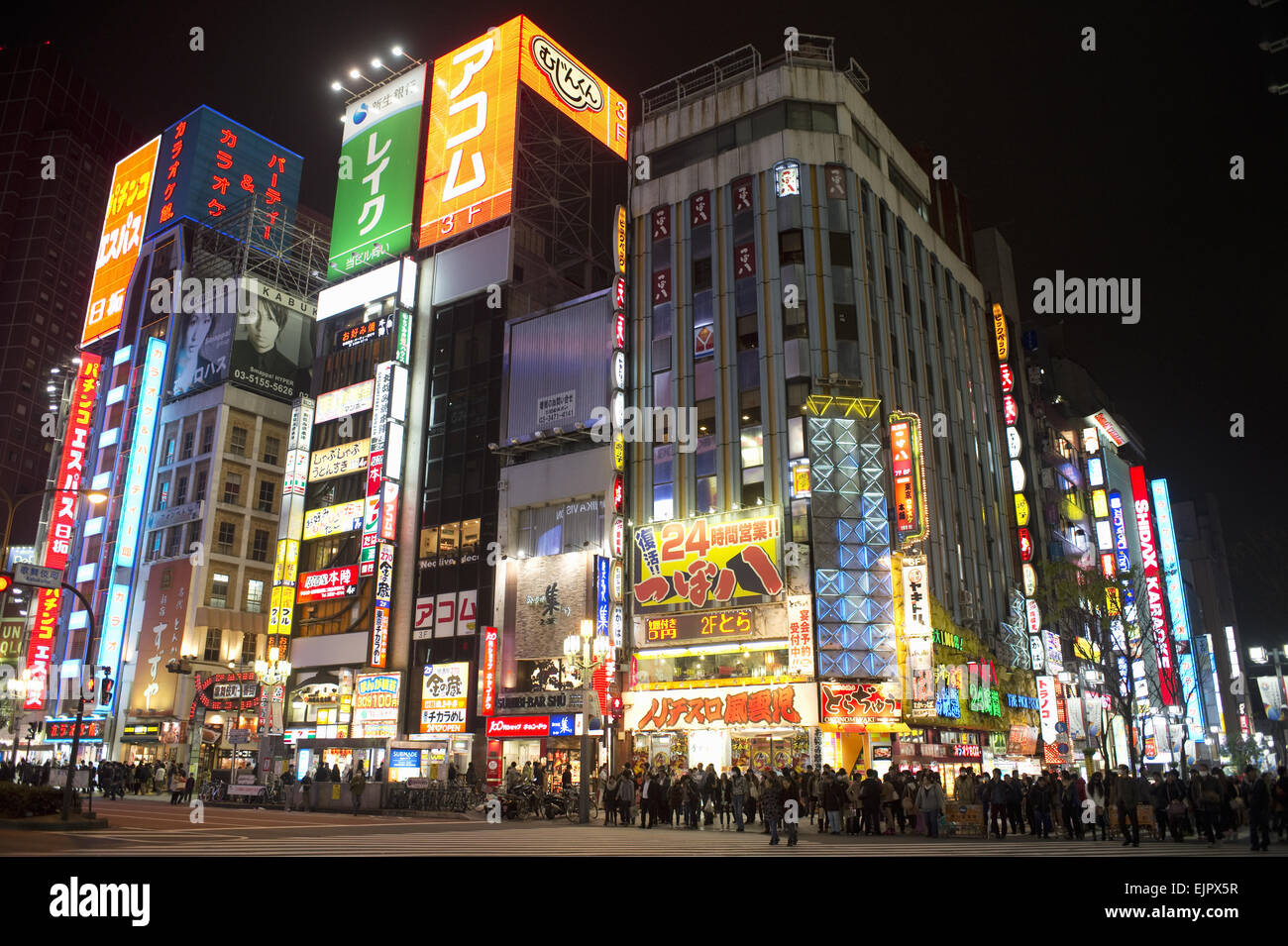 Stadtstraße mit Menschen und Lichtwerbung an Gebäuden in der Nacht, Tokio, Honshu, Japan, März Stockfoto