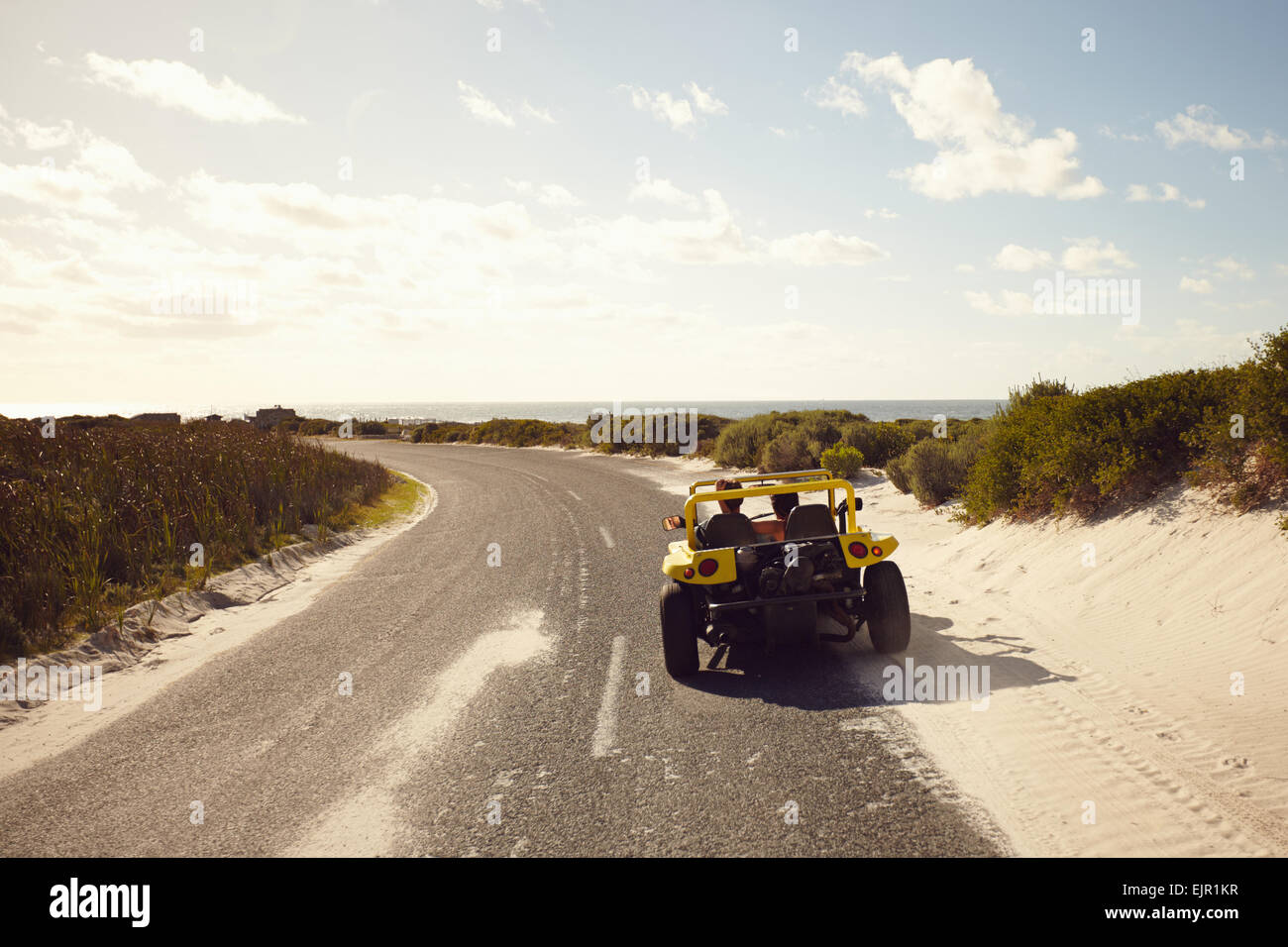 Rückansicht des jungen Paares fahren auf einer Landstraße zum Strand an einem sonnigen Tag. Paar auf Road-Trip in ein kleines Auto. Stockfoto