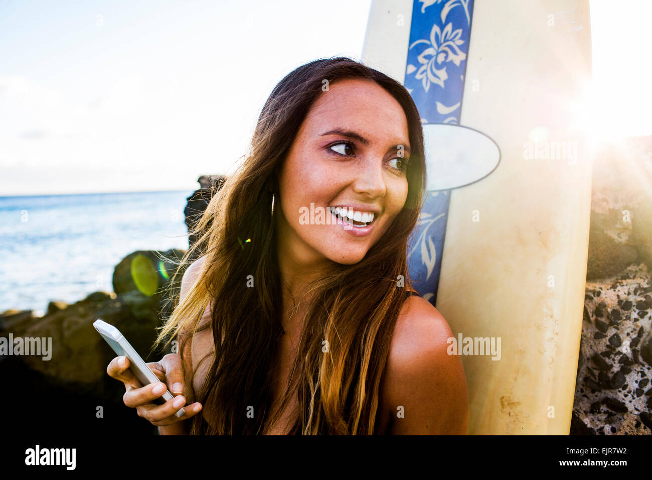 Kaukasische Frau mit Handy in der Nähe von Surfbrett Stockfoto