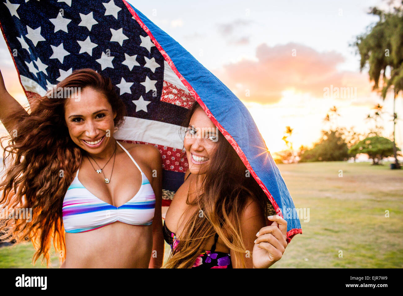 Frauen stehen unter amerikanischer Flagge Quilt bei Sonnenuntergang Stockfoto