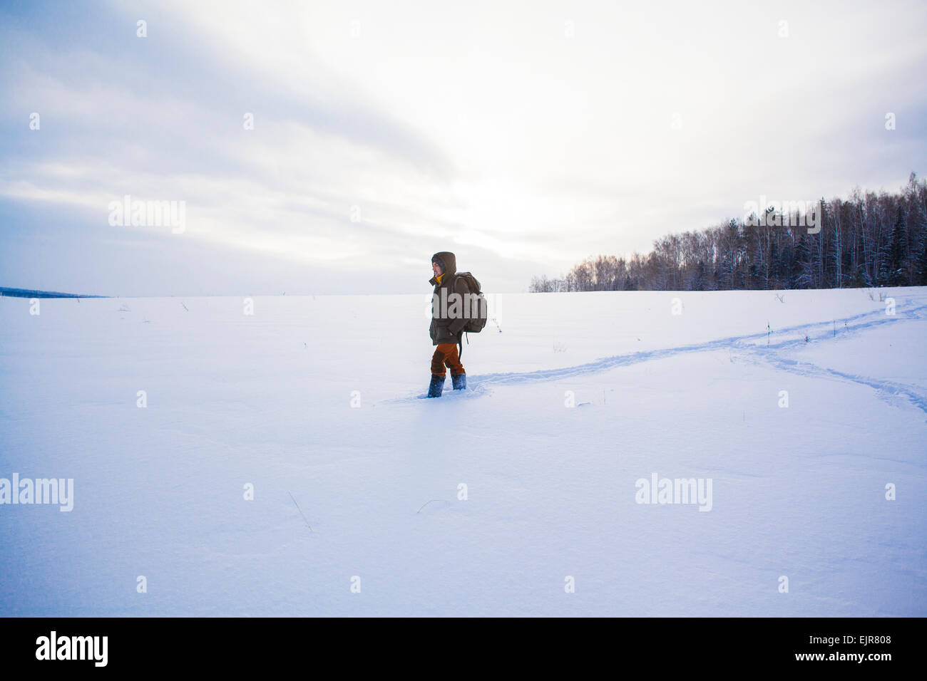 Gemischte Rassen Mann zu Fuß in schneebedecktes Feld Stockfoto