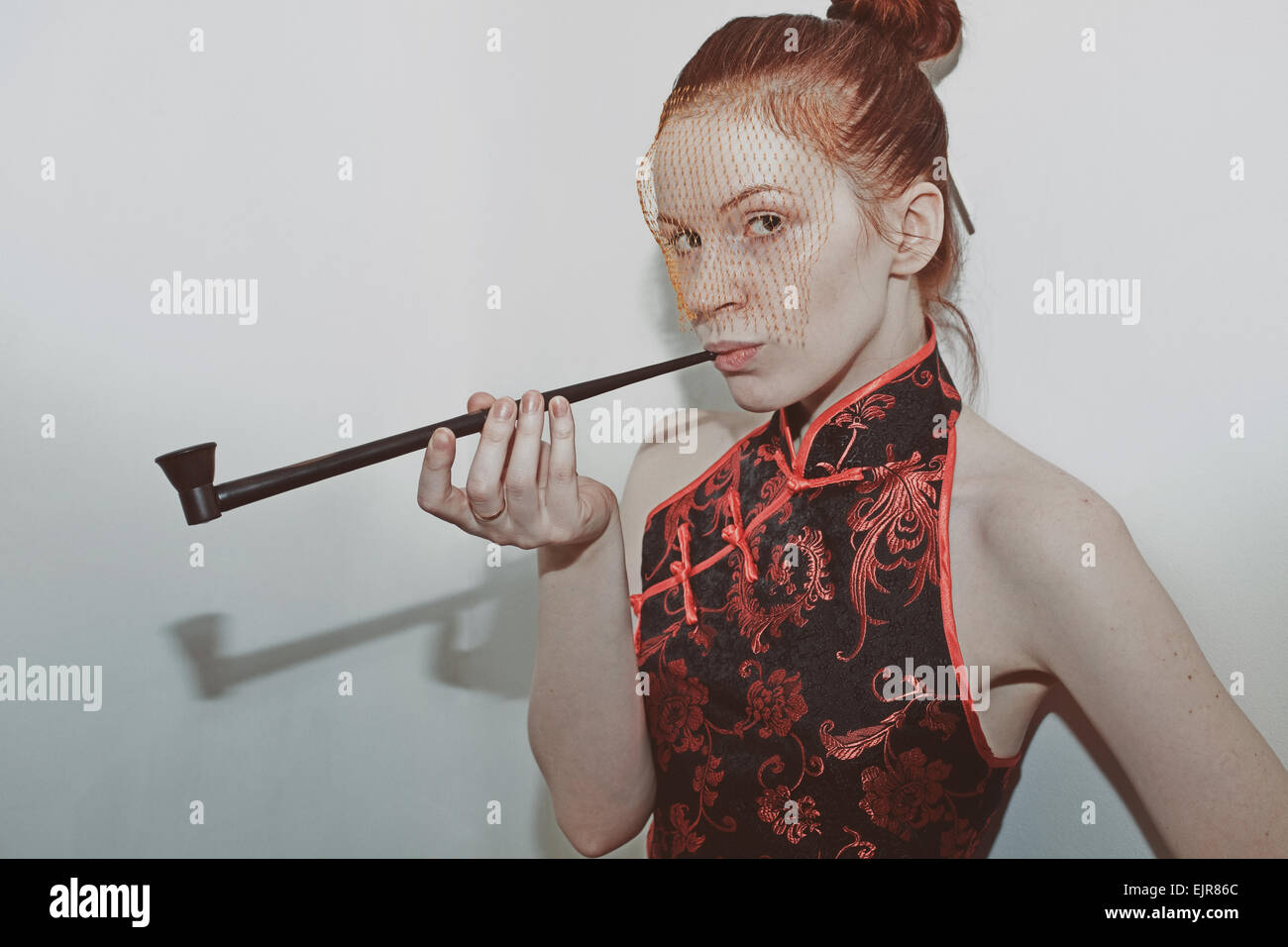 Porträt einer jungen Frau in einem japanischen Kleid und Schleier mit einem Rohr Stockfoto