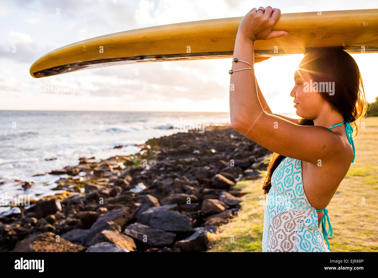 Pacific Islander Surfer mit Surfbrett auf felsigen Strand Stockfoto