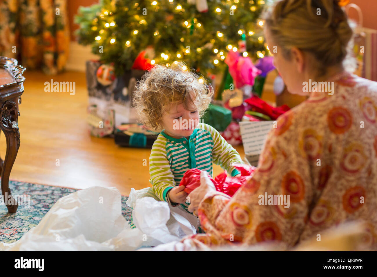 Kaukasische Mutter und Baby Sohn Eröffnung präsentiert Weihnachtsbaum Stockfoto