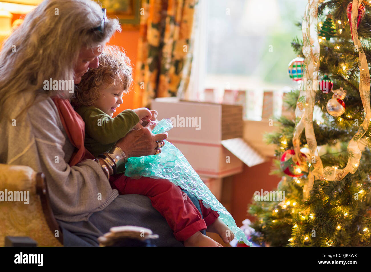 Kaukasische Großmutter und Enkel Eröffnung präsentiert Weihnachtsbaum Stockfoto