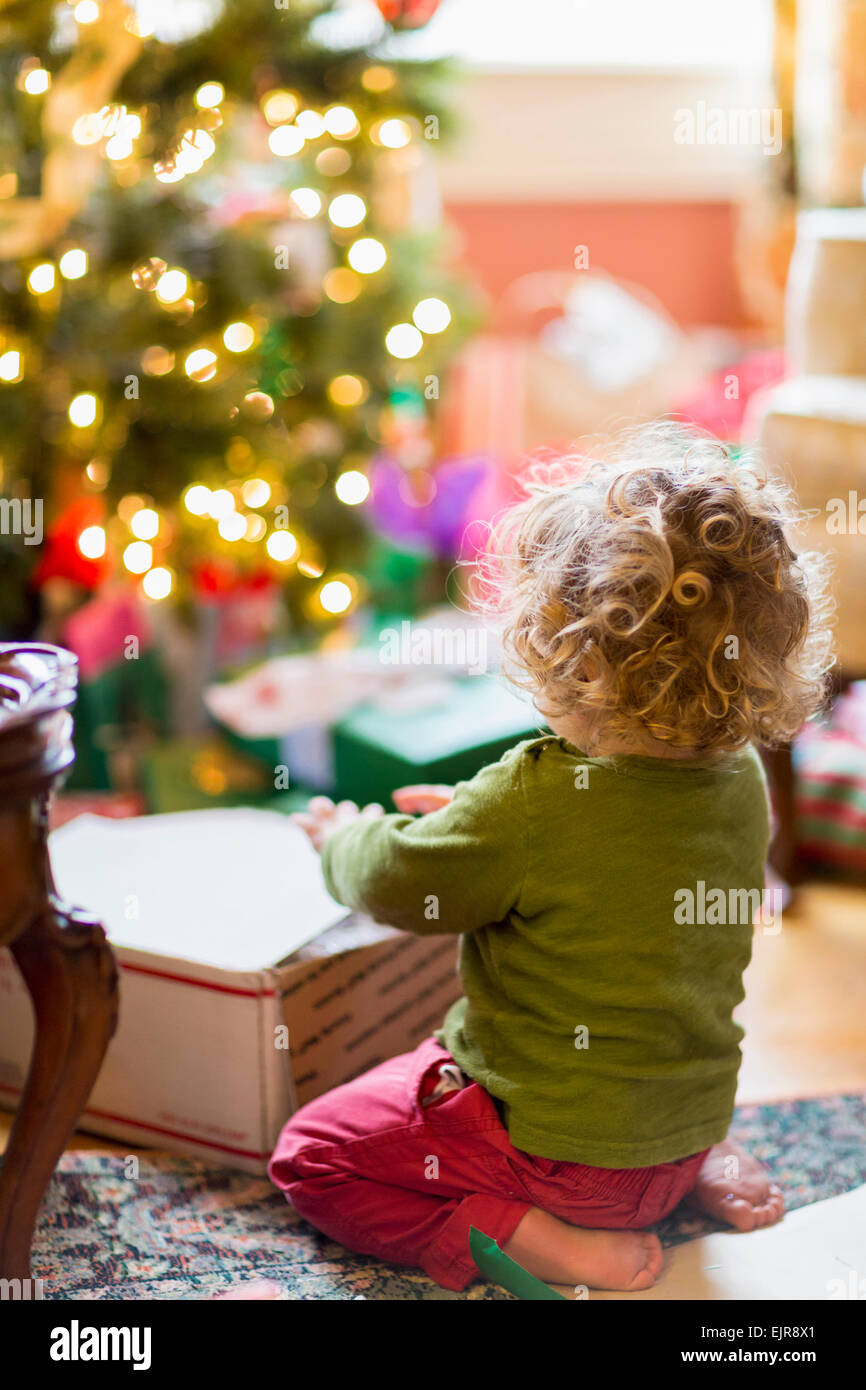 Kaukasische Babyjungen Eröffnung präsentiert Weihnachtsbaum Stockfoto