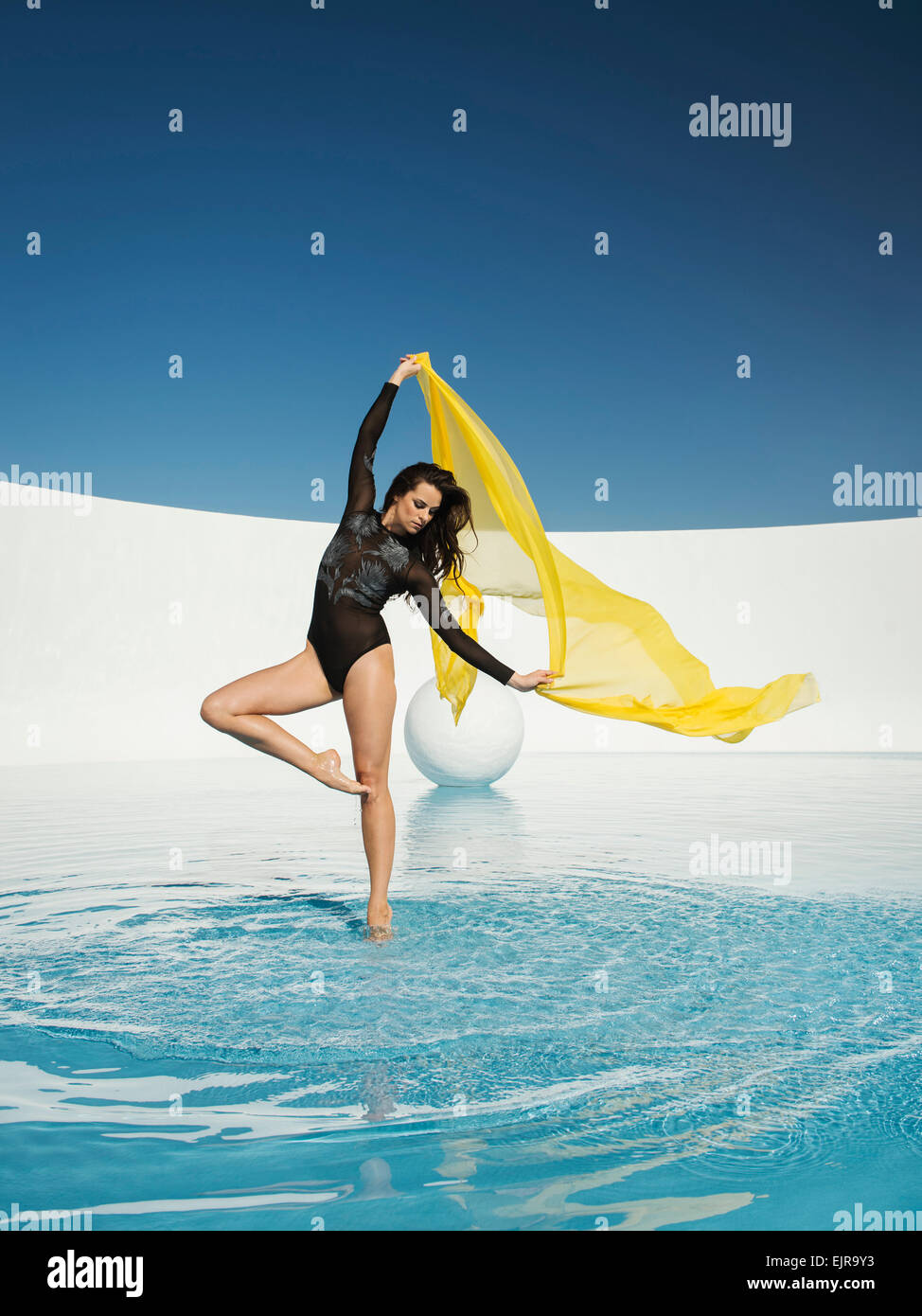 Kaukasische Frau tanzt mit Stoff auf Wasseroberfläche Stockfoto