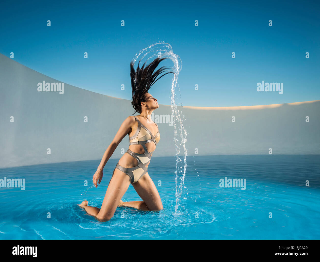 Kaukasische Frau wirft Haar am Schwimmbad Stockfoto