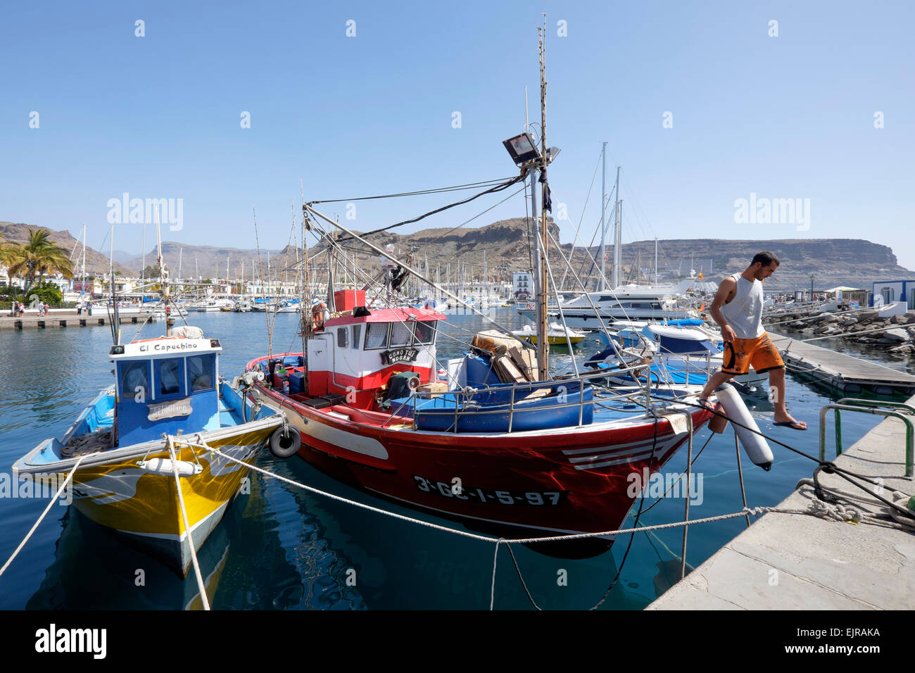 Ein Fischer steigt aus seinem Boot vertäut im Hafen von Puerto de Mogan, Gran Canaria, Spanien Stockfoto