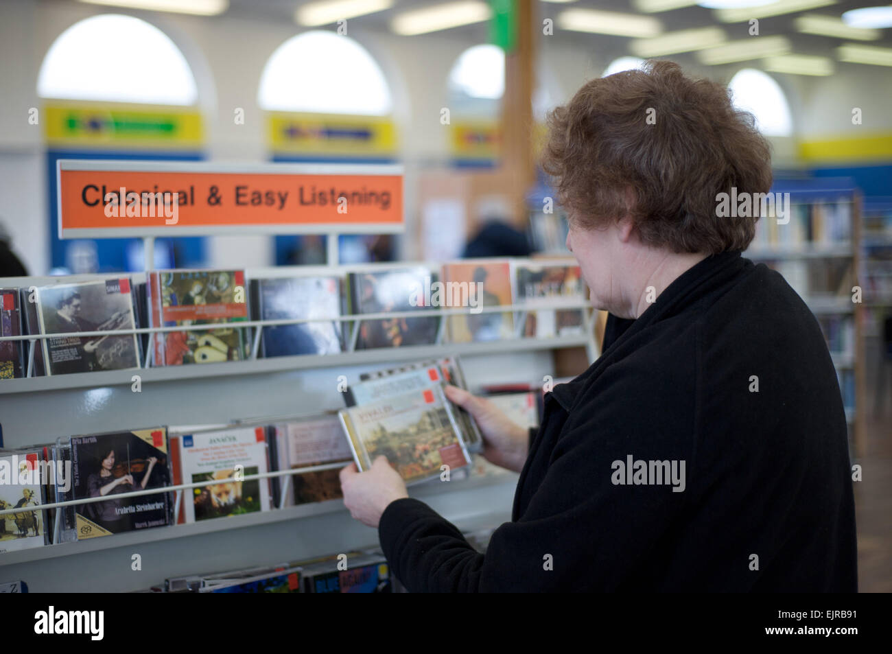 Eine Frau durchsucht die klassischen und Easy Listening Musik-CDs in einer öffentlichen Bibliothek Stockfoto