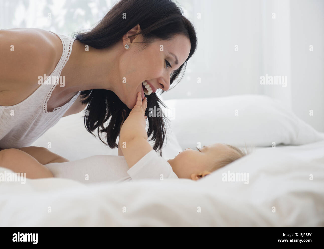 Mischlinge Mutter mit Baby im Bett spielen Stockfoto